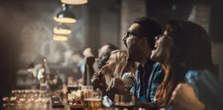 Group of cheerful fans cheering for their team in a bar.