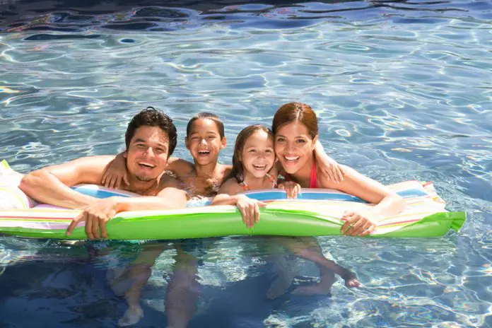 A Hispanic family swimming in a pool and enjoying McAllen living.